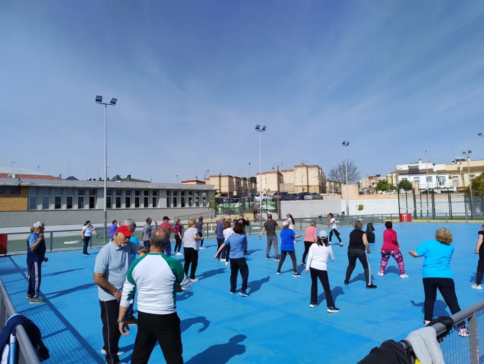 Grupo de personas mayores realizando ejercicio al aire libre en una pista deportiva de Dos Hermanas