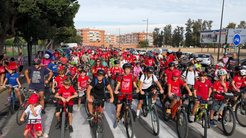 Numerosas personas con bicicletas y camisetas rojas recorren las calles de Montequinto